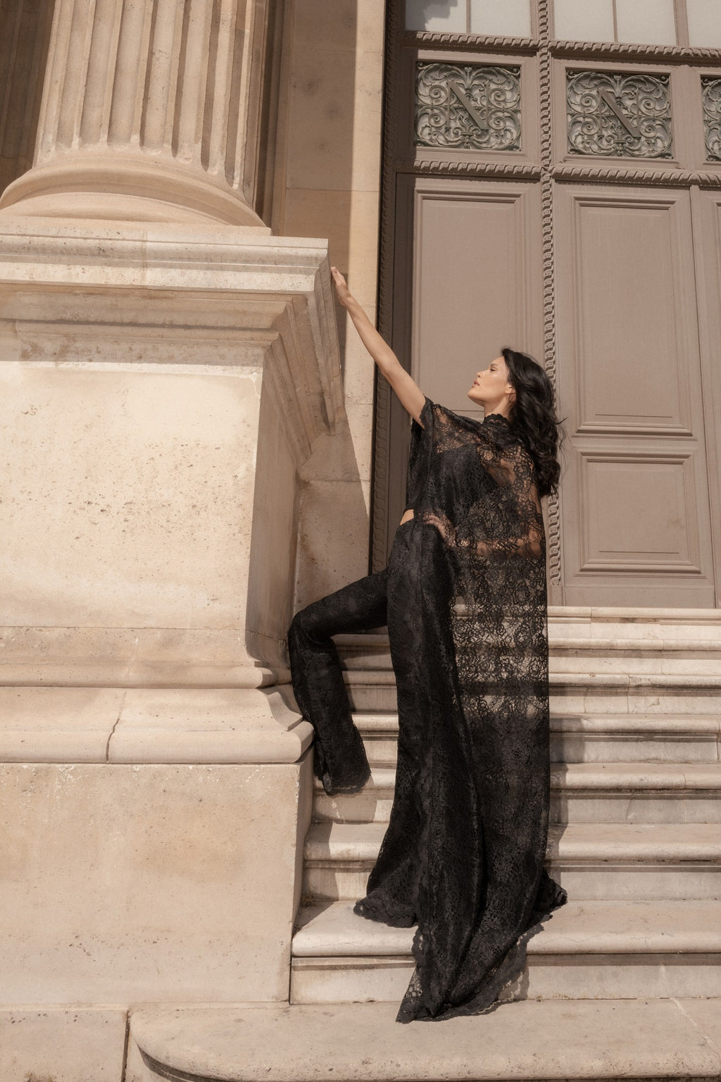 Black lace cape and corset set, side view, worn between classical stone columns.