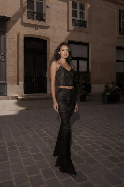 Black wide-leg Femme Pants worn with a black top, full length, in a Paris courtyard.