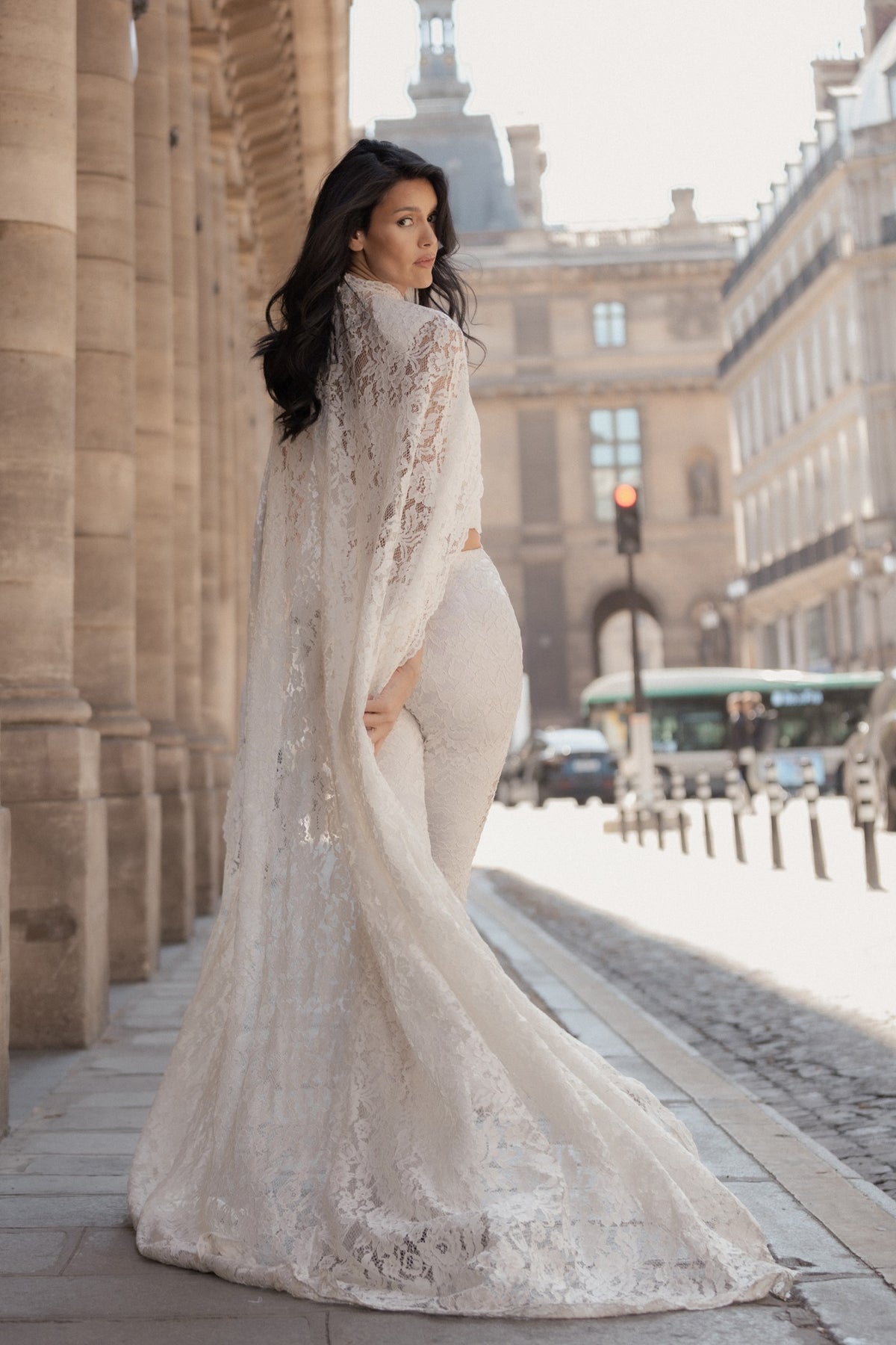 White lace wide-leg trousers and cape seen from behind, the lace trailing.