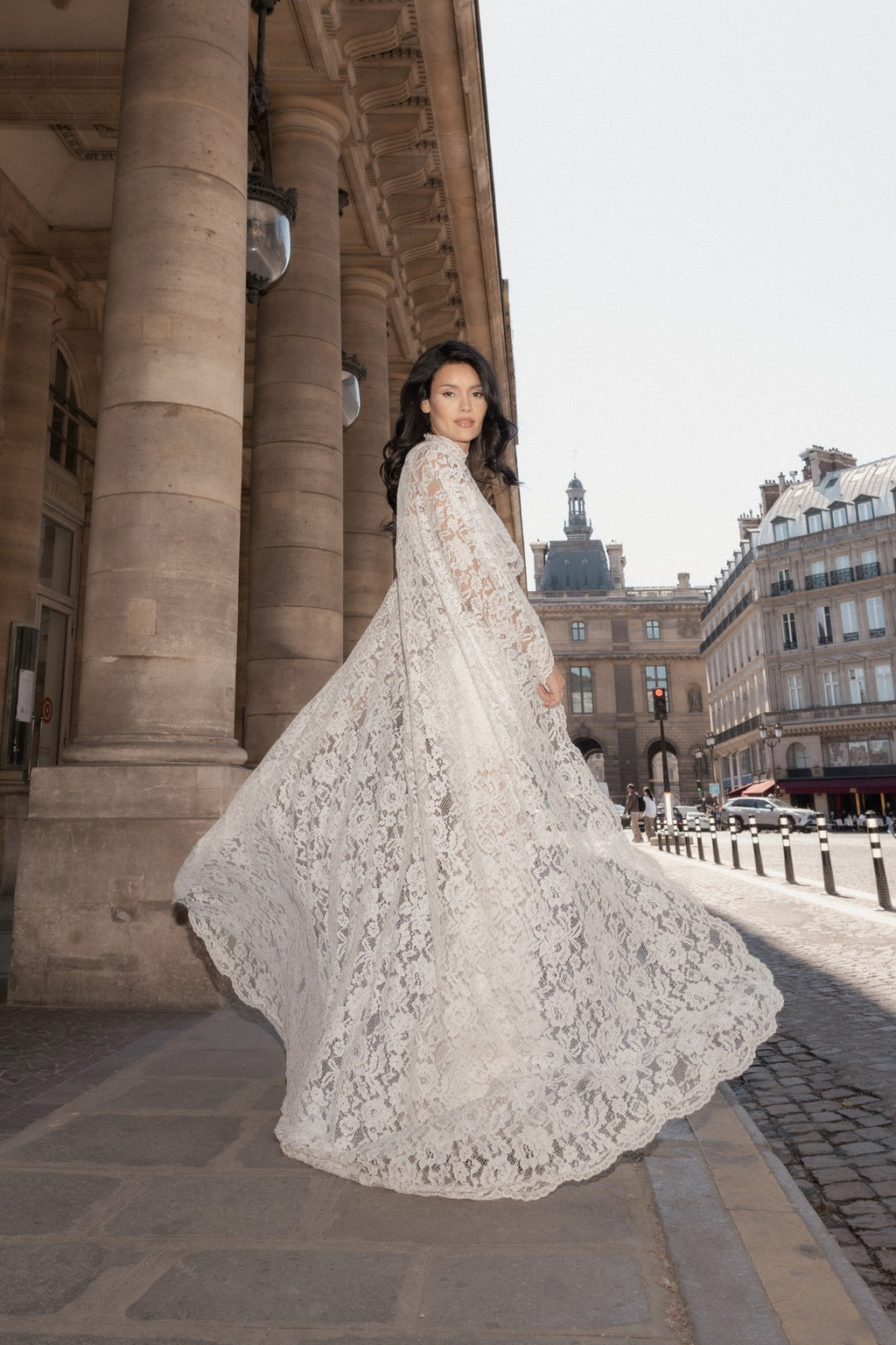 White lace cape and corset set held open to show the full width of the cape, in a Paris courtyard.
