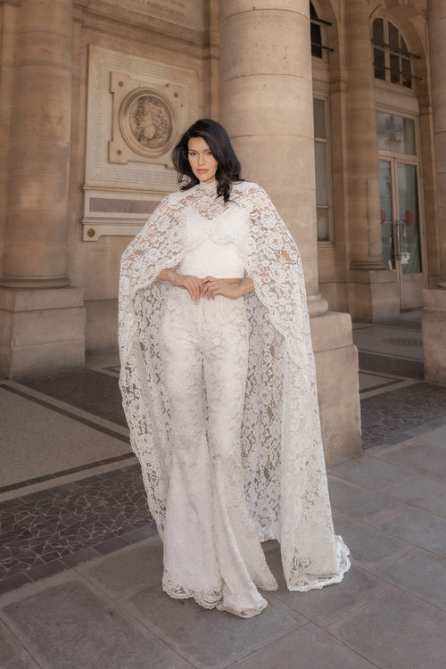 White Chantilly lace Femme Cape and corset set, full length, front view among stone columns.